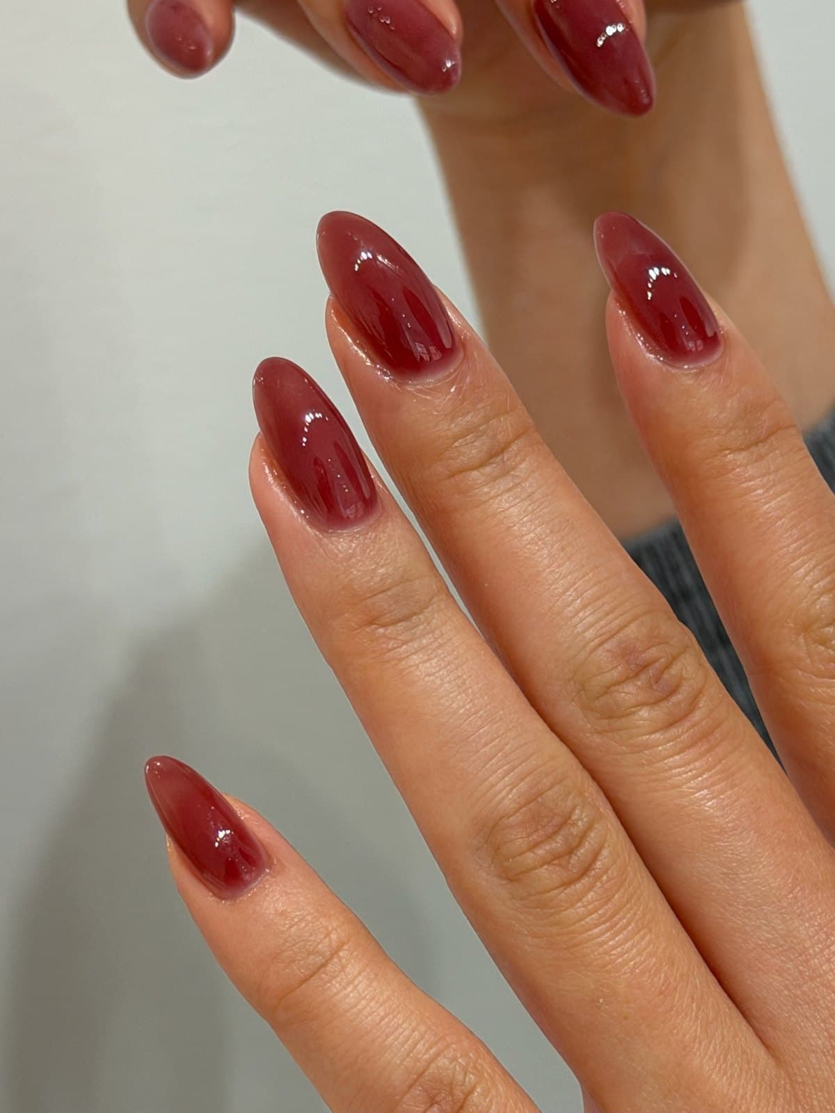 Long almond gel nails in glossy deep burgundy red at Joy Nail Studio Vancouver