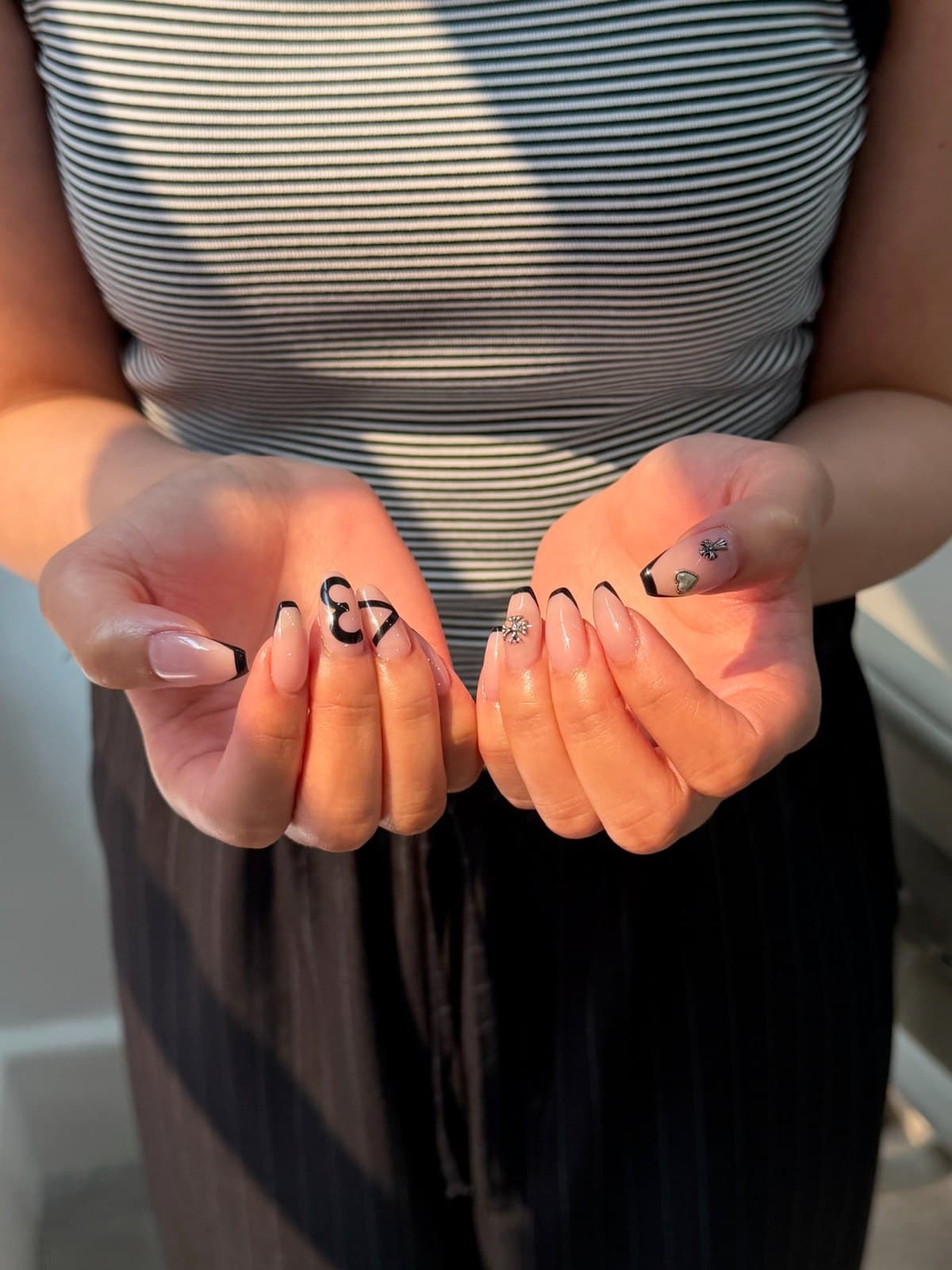 Gel nails in nude and black with hand-painted line art at Joy Nail Studio Vancouver