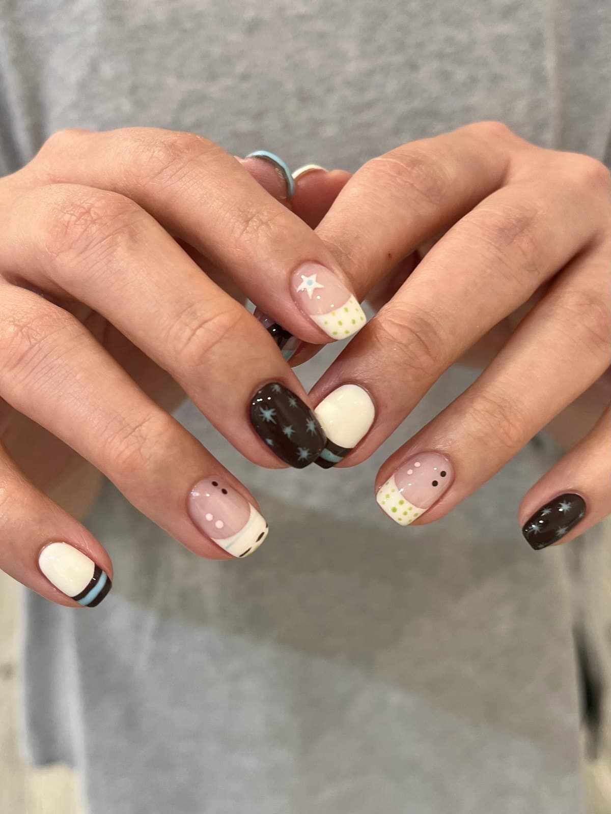 Short square gel nails in cream, chocolate and black with tiny star art at Joy Nail Studio Vancouver