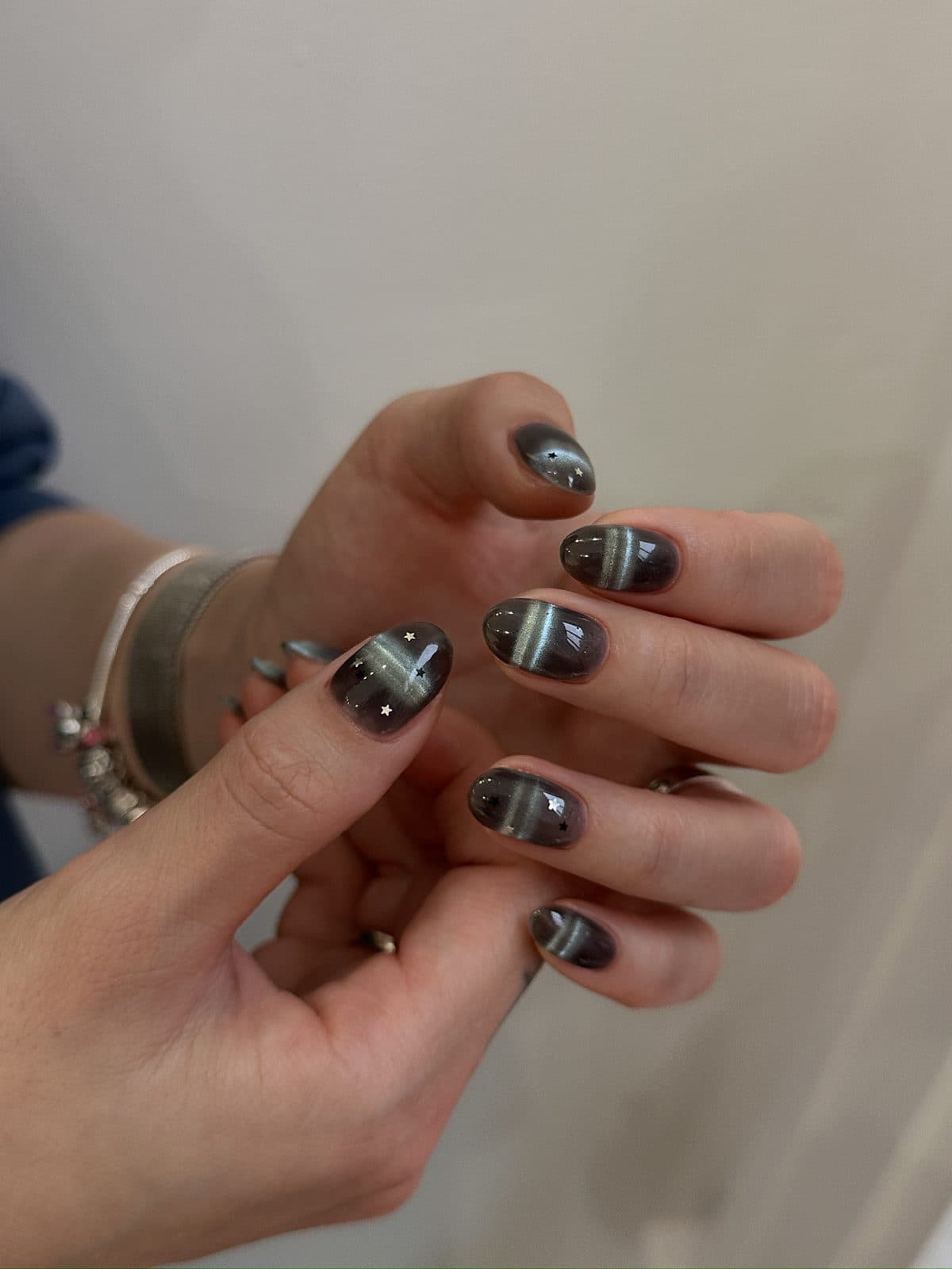 Short round gel nails in a charcoal cat-eye with a star accent at Joy Nail Studio Vancouver