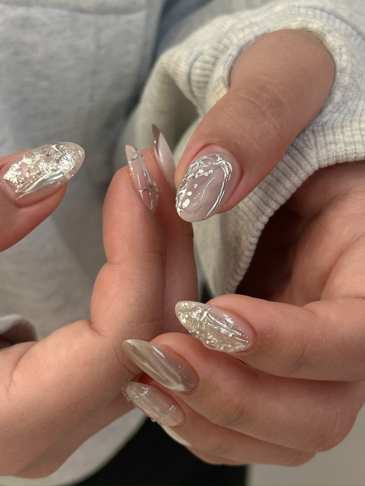 Close-up of silver foil and marbling under a chrome gel finish at Joy Nail Studio Vancouver