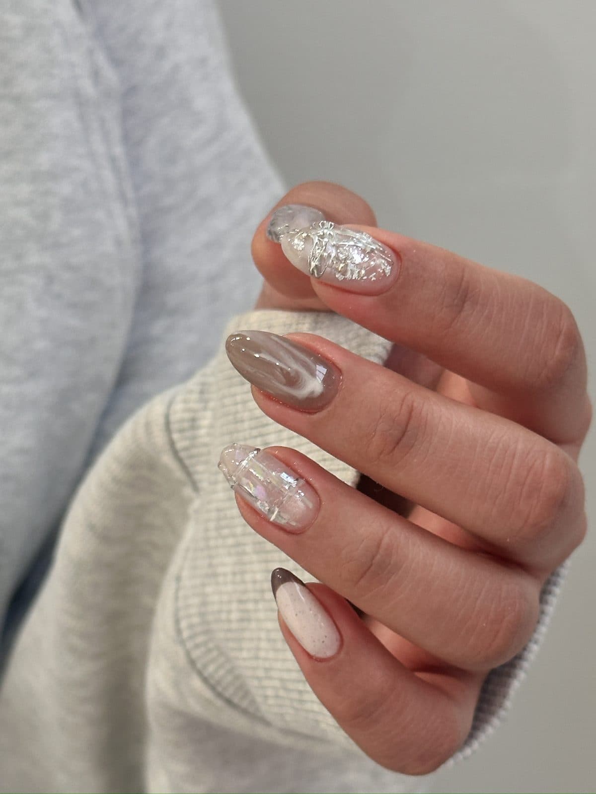 Almond gel nails in clear chrome with silver foil and marble detail at Joy Nail Studio Vancouver