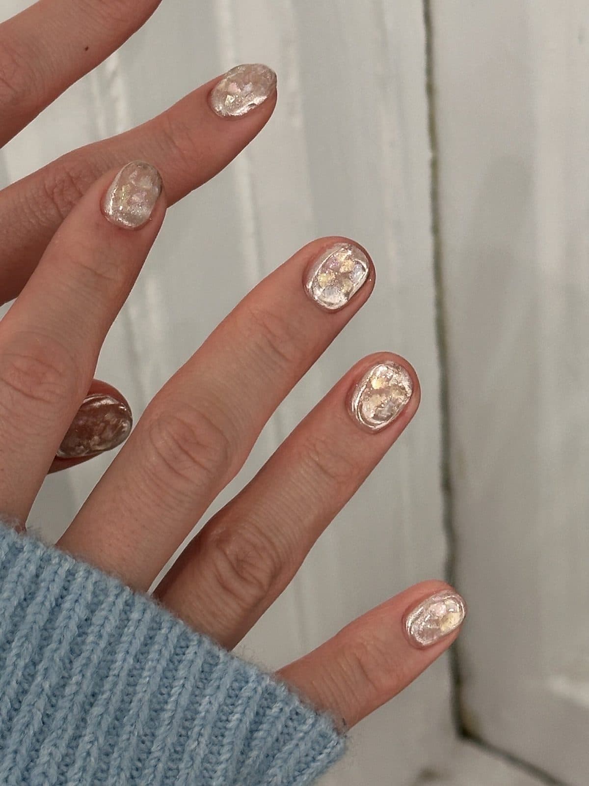 Short gel nails in sheer nude with gold foil and pearl fragments at Joy Nail Studio Vancouver