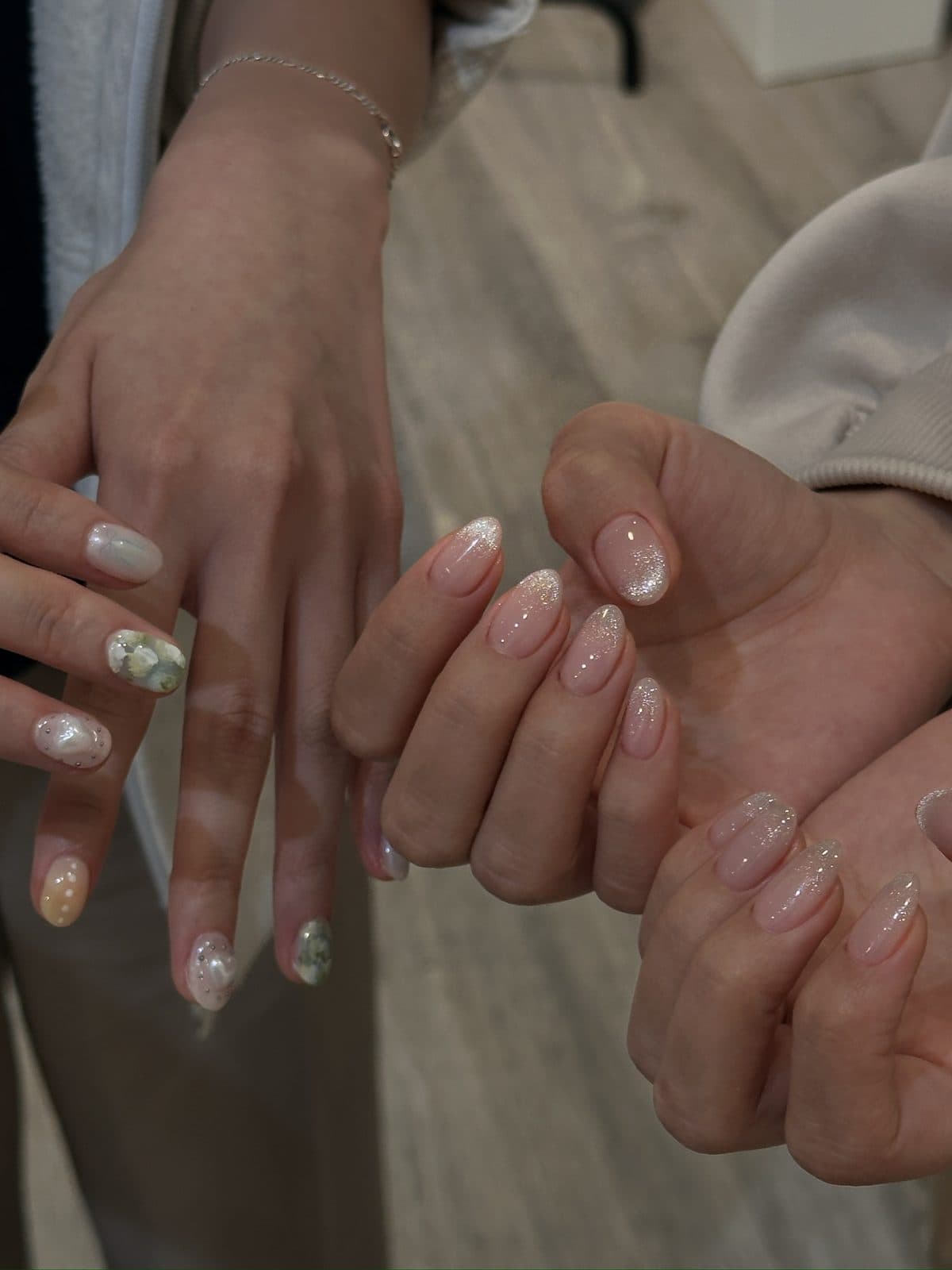 Two sets of gel nails, one in glitter ombre and one with flower art at Joy Nail Studio Vancouver
