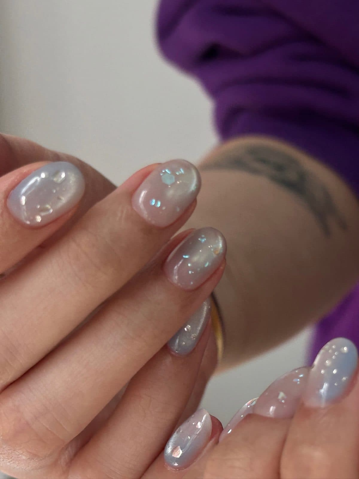 Short gel nails in soft grey with iridescent flakes at Joy Nail Studio Vancouver