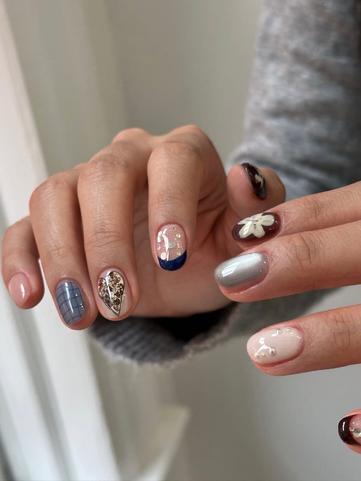 Gel nails mixing navy stars, blue plaid and a 3D white flower at Joy Nail Studio Vancouver