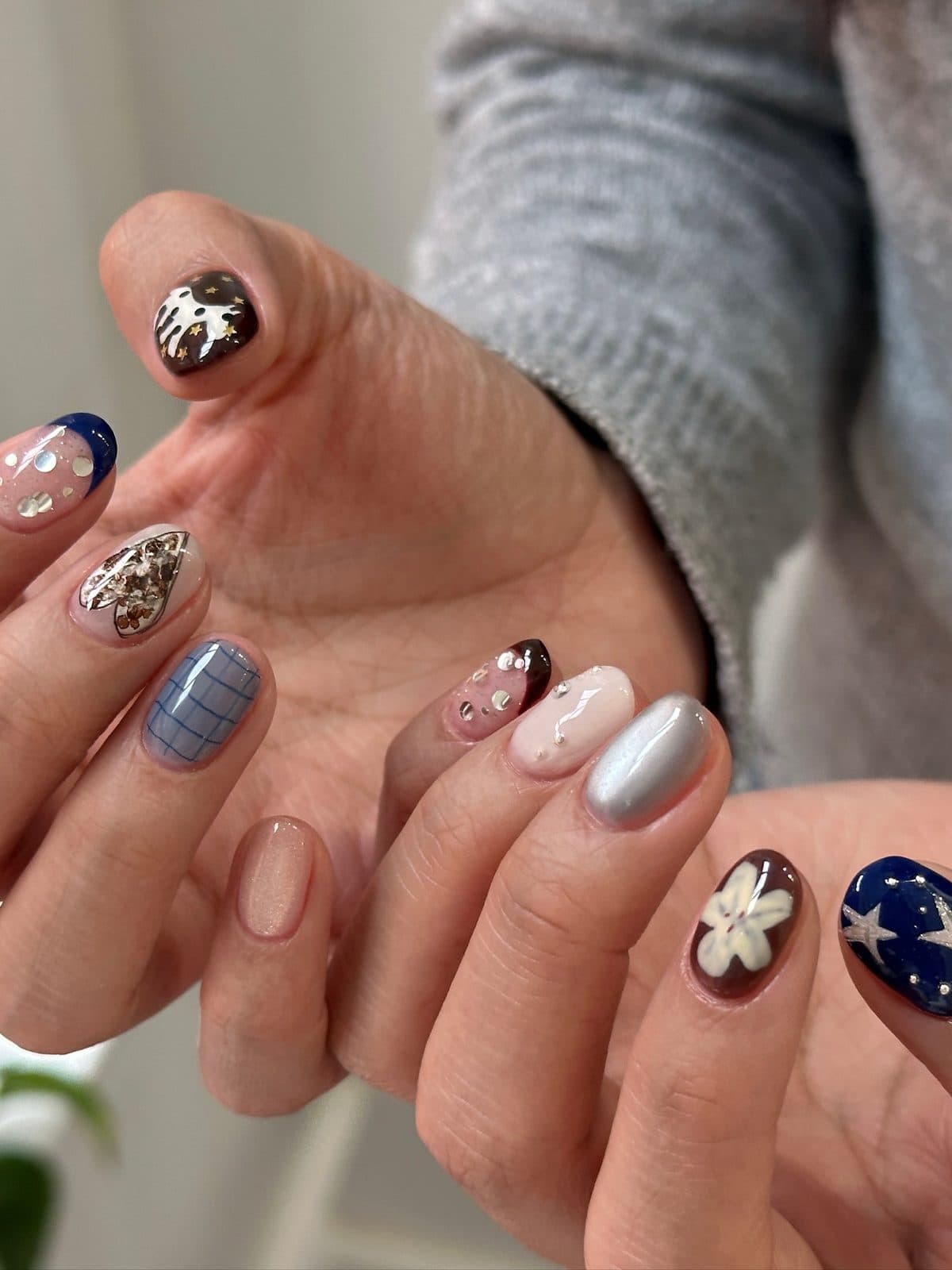 Gel nails on both hands mixing navy, plaid, chrome and 3D flower art at Joy Nail Studio Vancouver