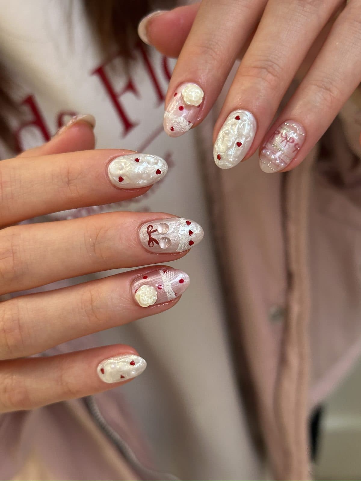 Gel nails in pearl white with red hearts, bows and 3D relief art at Joy Nail Studio Vancouver