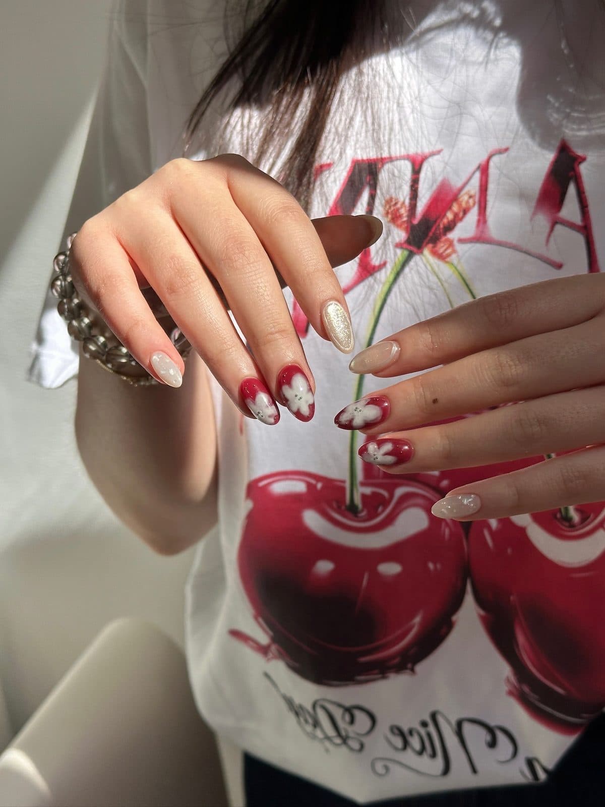 Long almond gel extensions in deep red with hand-painted white flowers at Joy Nail Studio Vancouver