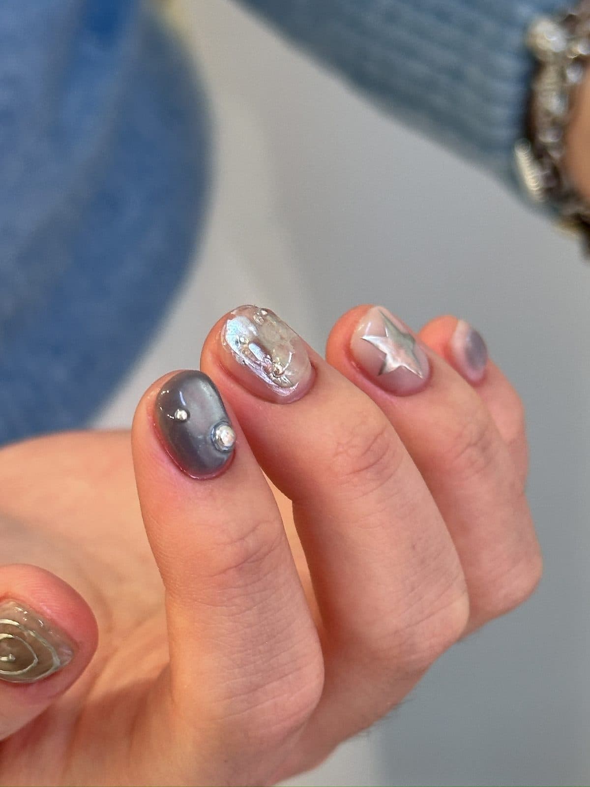 Close-up of a silver wire outline and star on a blue chrome gel nail at Joy Nail Studio Vancouver