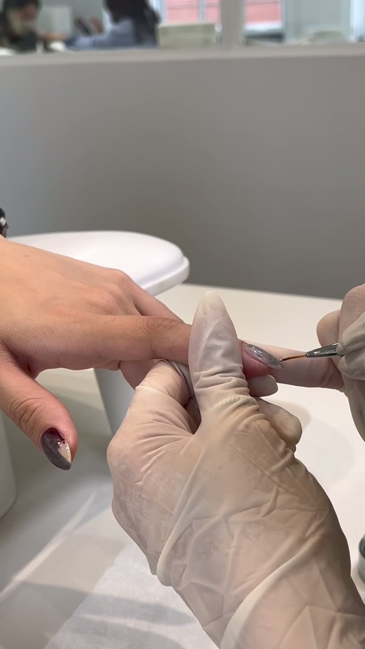 A nail artist shaping and painting a client's gel nails at Joy Nail Studio Vancouver