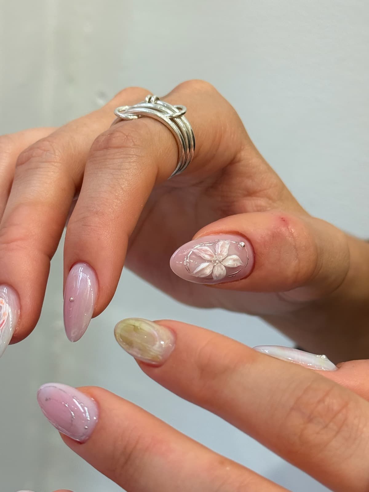 Milky pink Korean gel almond nails with a white flower accent by Joy Nail Studio Vancouver