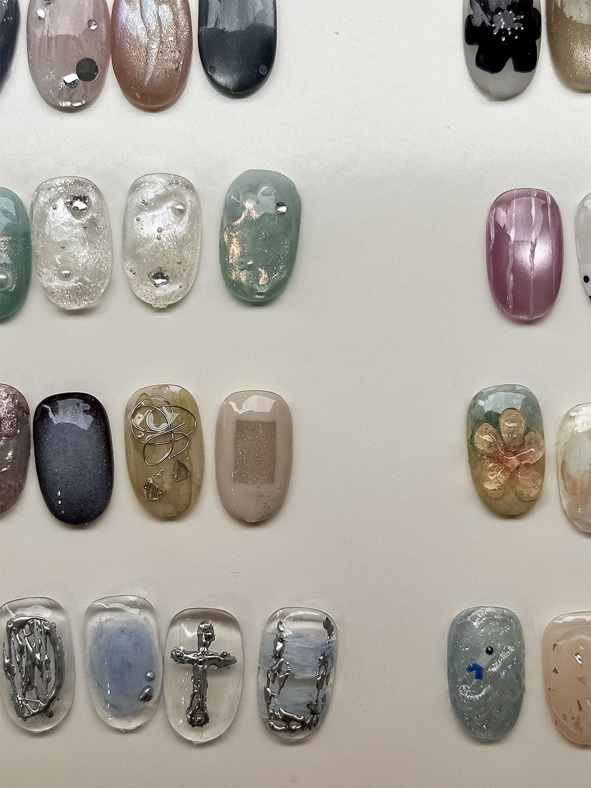 Board of August nail art sample tips with shimmer, soft greens, marble and fine metal details at Joy Nail Studio Vancouver